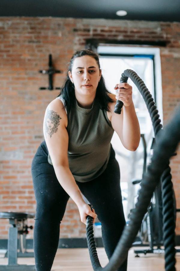 Une femme exercant avec des cordes de combat dans une salle deixknmt